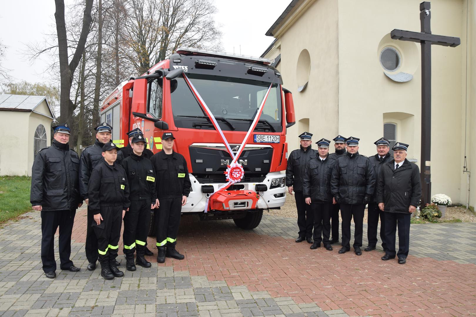 Zdjęcie przedstawia strażaków pozujących przy wozie bojowym