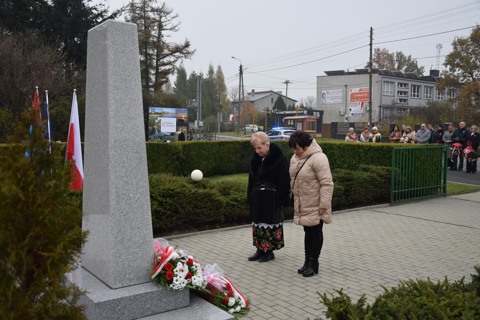 Zdjęcie przedstawia moment wręczenia kwiatów pod pomnikiem