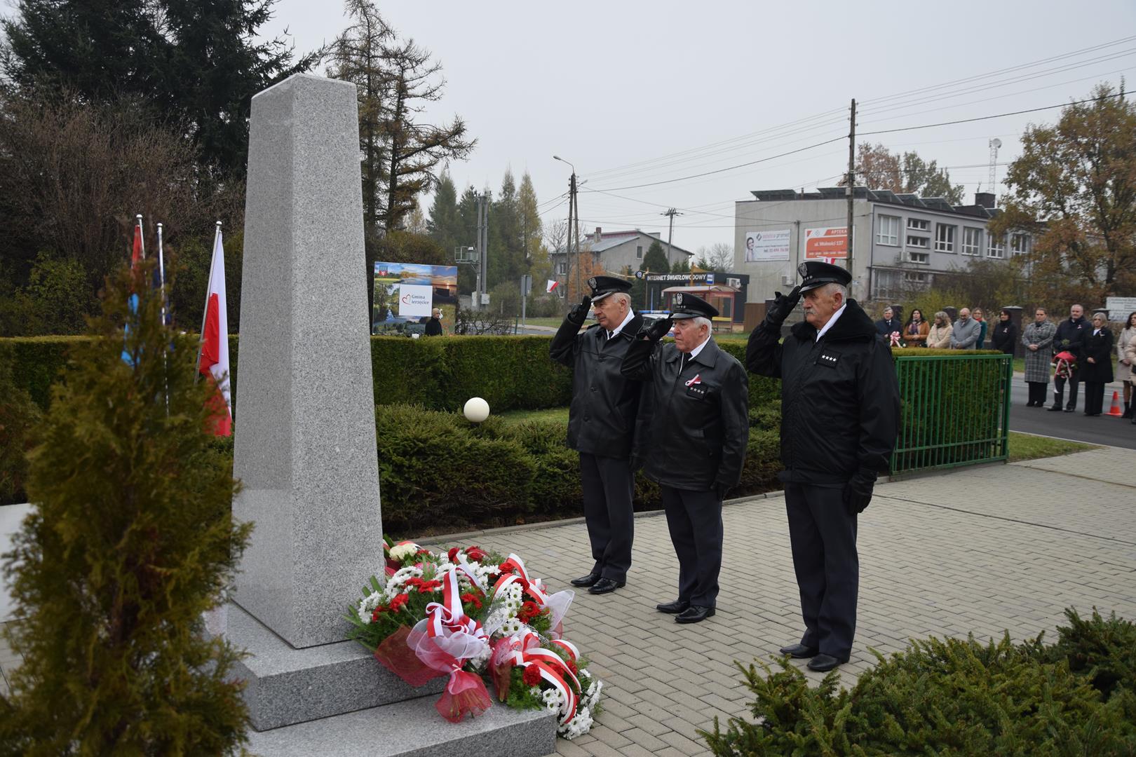 Zdjęcie przedstawia moment wręczenia kwiatów pod pomnikiem