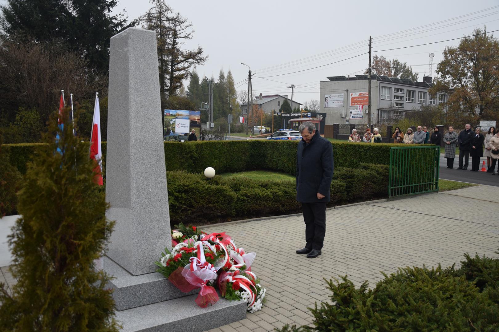 Zdjęcie przedstawia moment wręczenia kwiatów pod pomnikiem