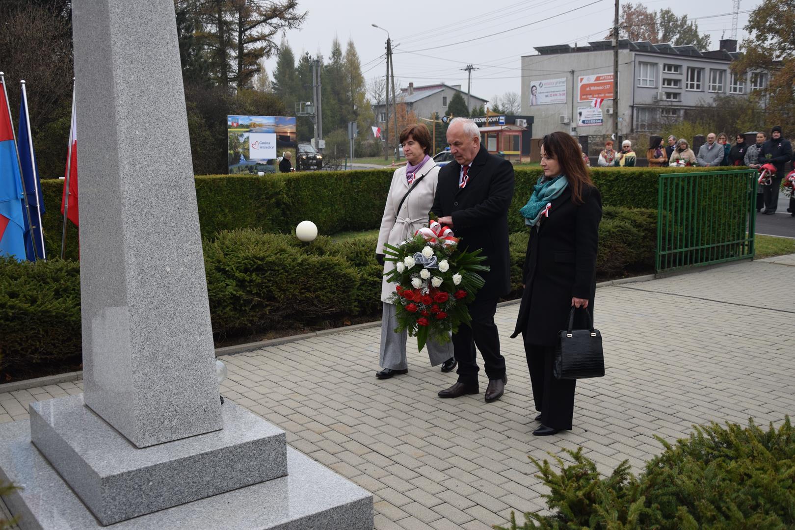 Zdjęcie przedstawia moment wręczenia kwiatów pod pomnikiem