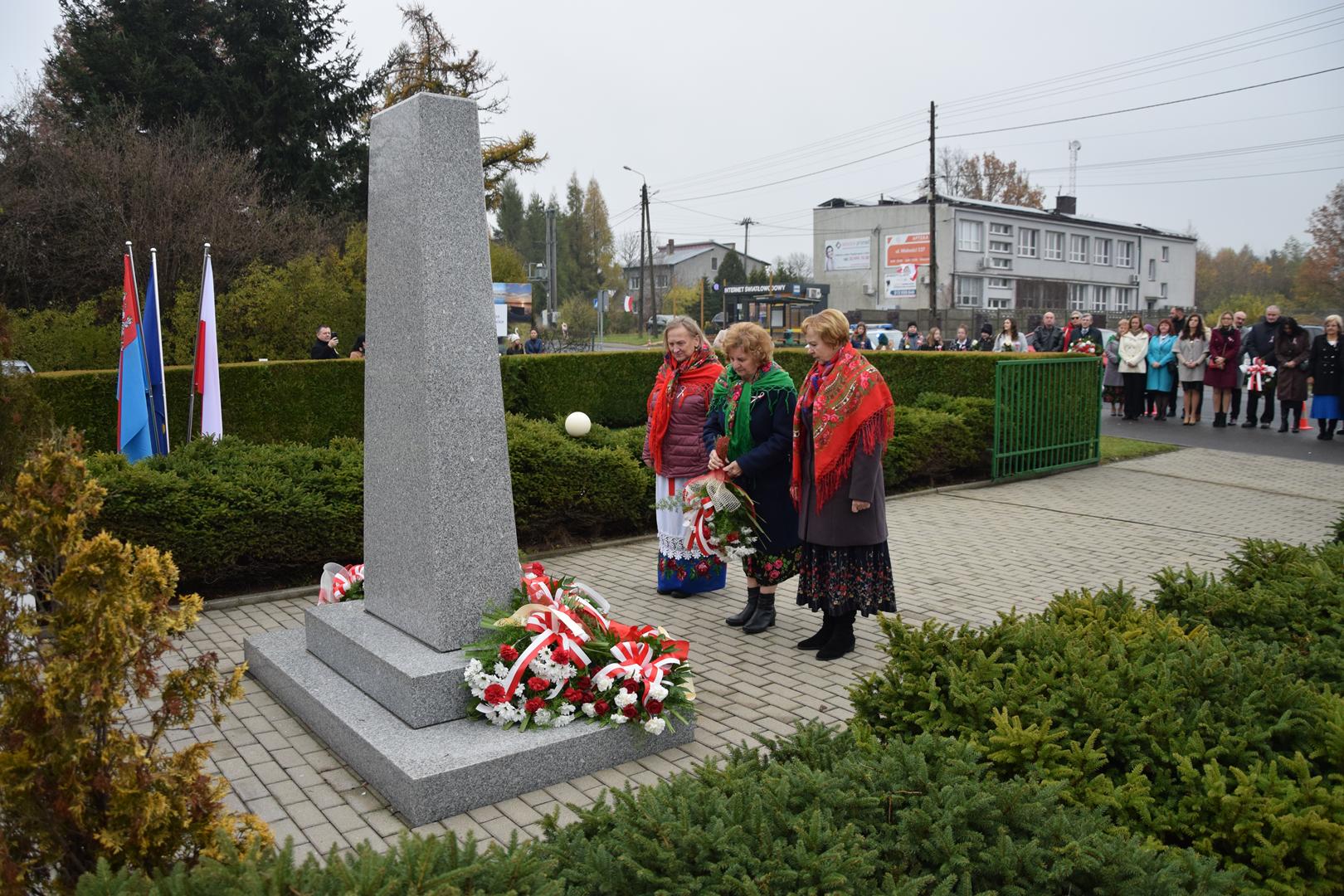 Zdjęcie przedstawia moment składania kwiatów pod pomnikiem