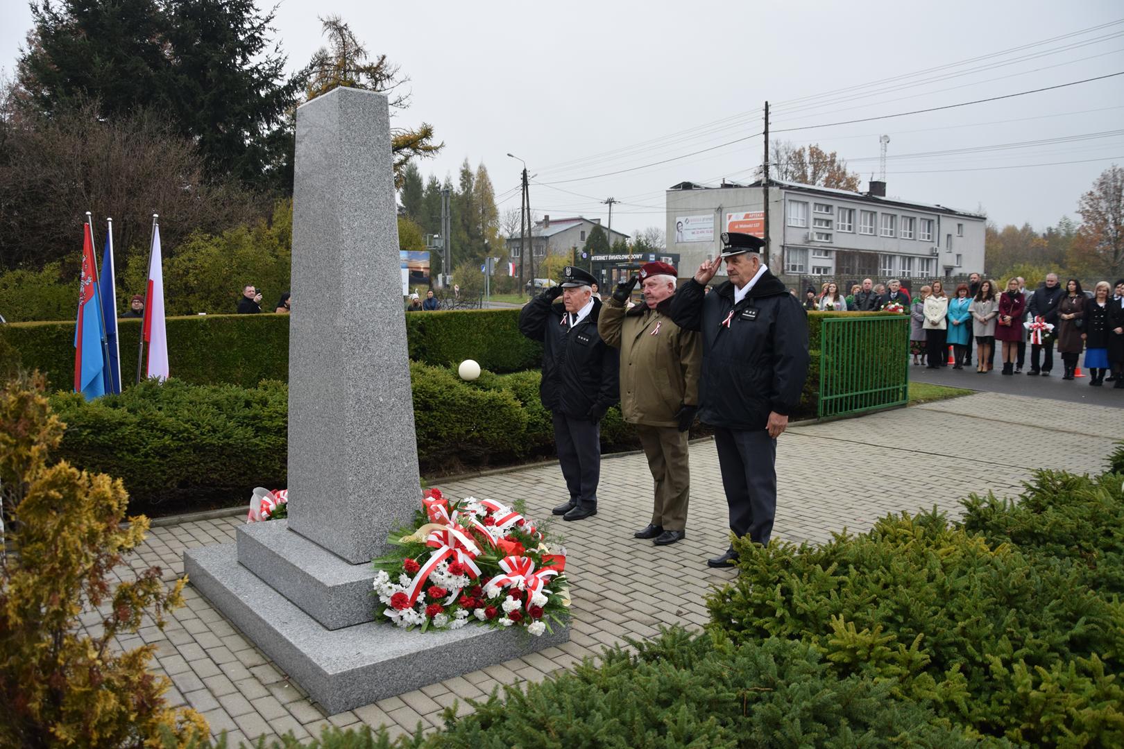 Zdjęcie przedstawia moment składania kwiatów pod pomnikiem