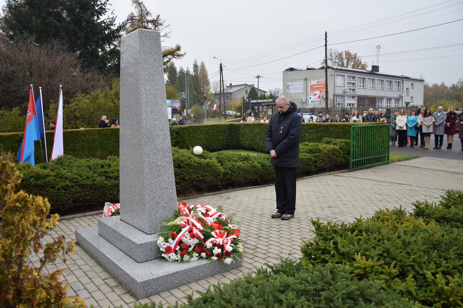 Zdjęcie przedstawia moment składania kwiatów pod pomnikiem