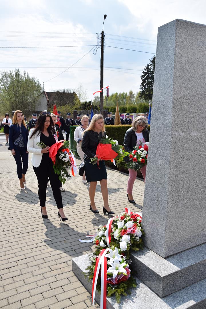 Zdjęcie przedstawiające moment złożenia kwiatów pod Pomnikiem Niepodległości przez przedstawicieli placówek oświatowych z terenu gminy