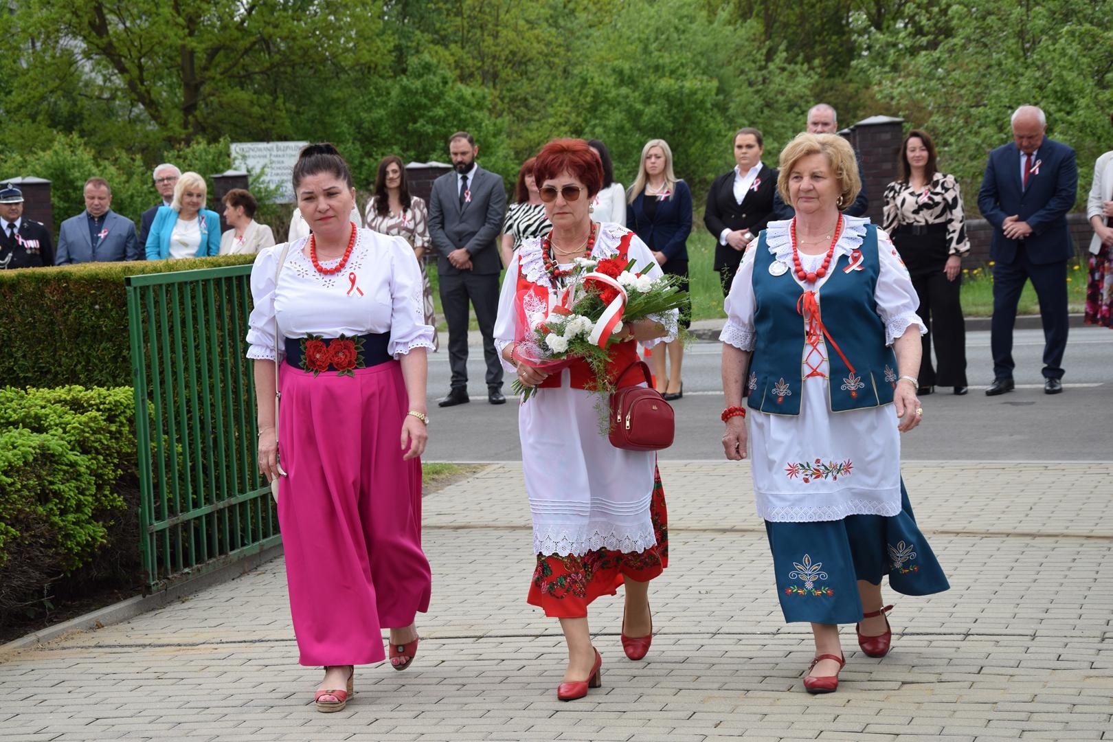Zdjęcie przedstawia moment składania kwiatów pod pomnikiem przez delegację Kół Gospodyń Wiejskich z terenu Gminy Mierzęcice
