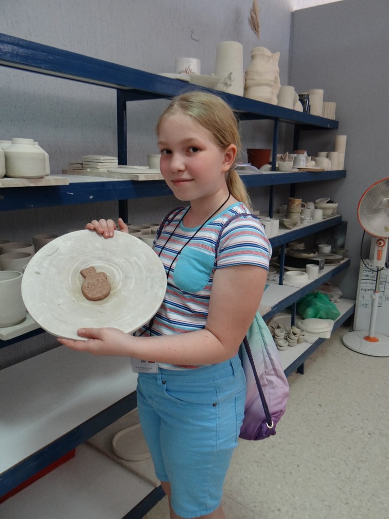 Zdjęcie przedstawiające dziecko trzymające talerz z glinianą figurką