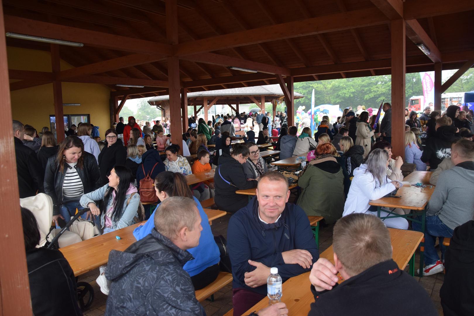 Zdjęcie przedstawia ludzi zgromadzonych pod wiatą