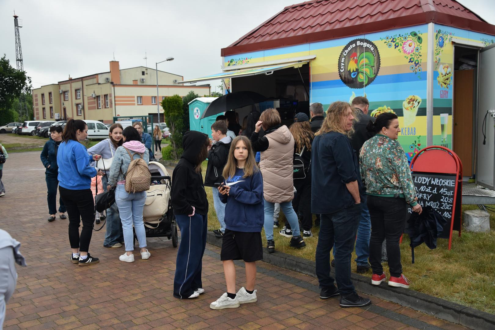 Zdjęcie przedstawia ludzi korzystających z usług foodtrucków