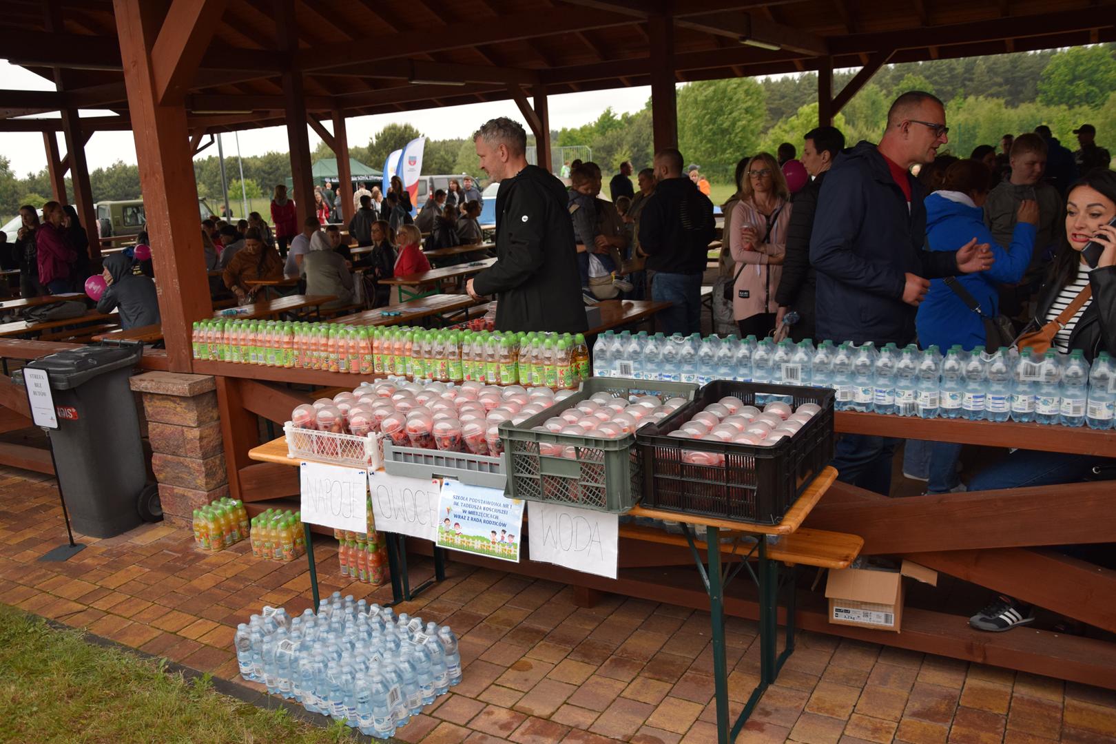 Zdjęcie przedstawia stoisko wód i soków na pikniku z okazji Dnia Dziecka