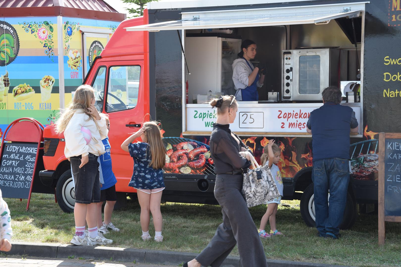 Zdjęcie przedstawia uczestników pikniku korzystających z oferty foodtrucków