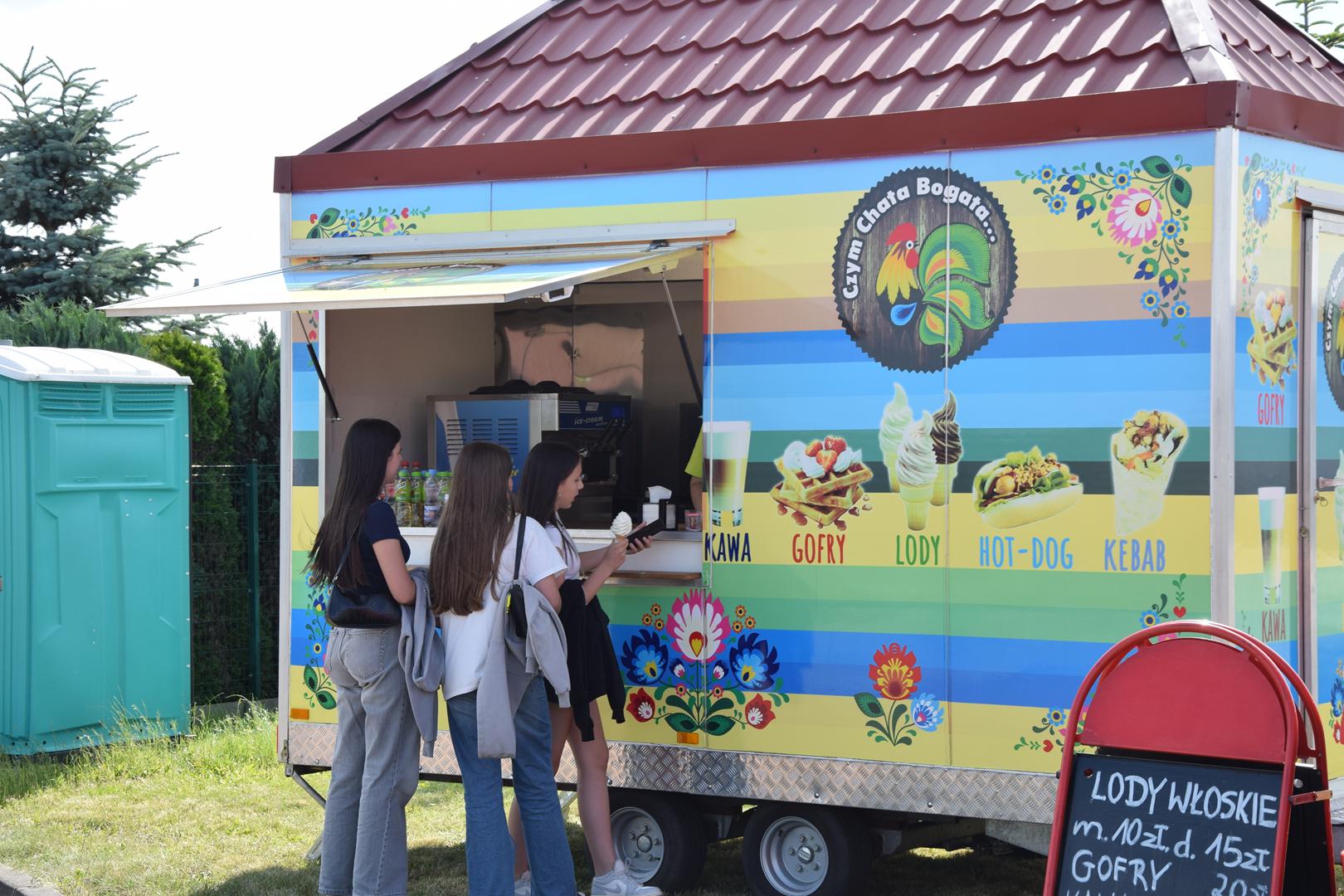 Zdjęcie przedstawia uczestników pikniku korzystających z oferty foodtrucków