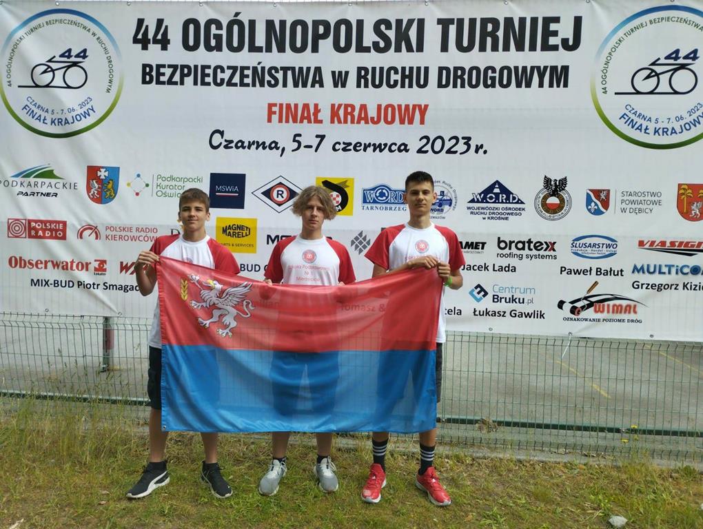 Zdjęcie przedstawia zawodników trzymających flagę gminy Mierzęcice