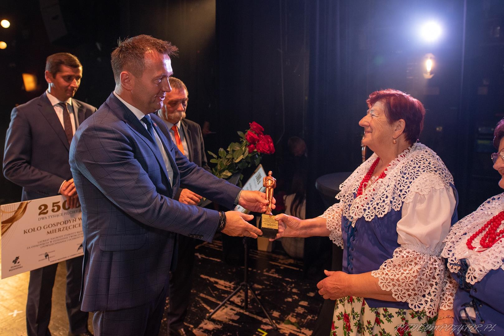 Zdjęcie przedstawia moment wręczenia nagrody dla KGW Mierzęcice II przez Starostę Będzińskiego Sebastiana Szaleńca
