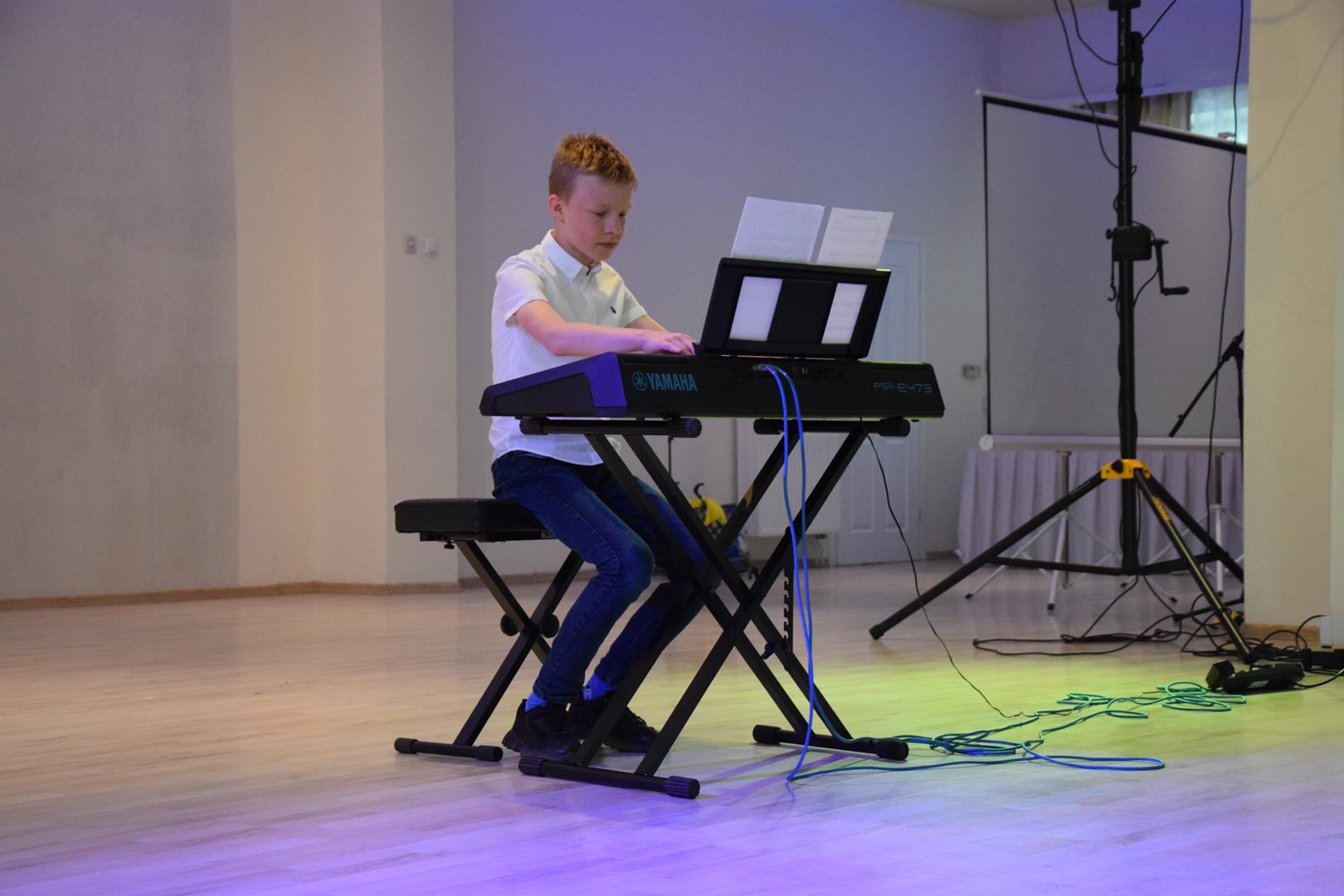 Zdjęcie przedstawiające prezentację gry na fortepianie uczestnika warsztatów muzycznych