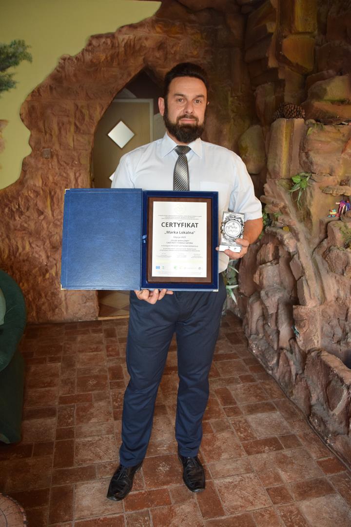 Zdjęcie przedstawiające Tomasza Satorę trzymającego dyplom "Marki lokalnej"