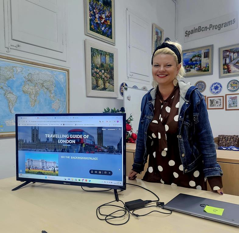 Zdjęcie przedstawia kobietę pozującą do zdjęcia przy komputerze