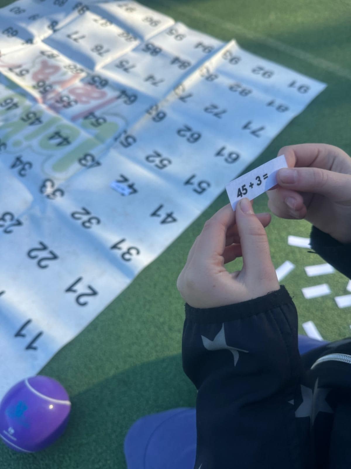 Zdjęcie przedstawia osobę trzymającą wydrukowane cyfry na kartkach papieru