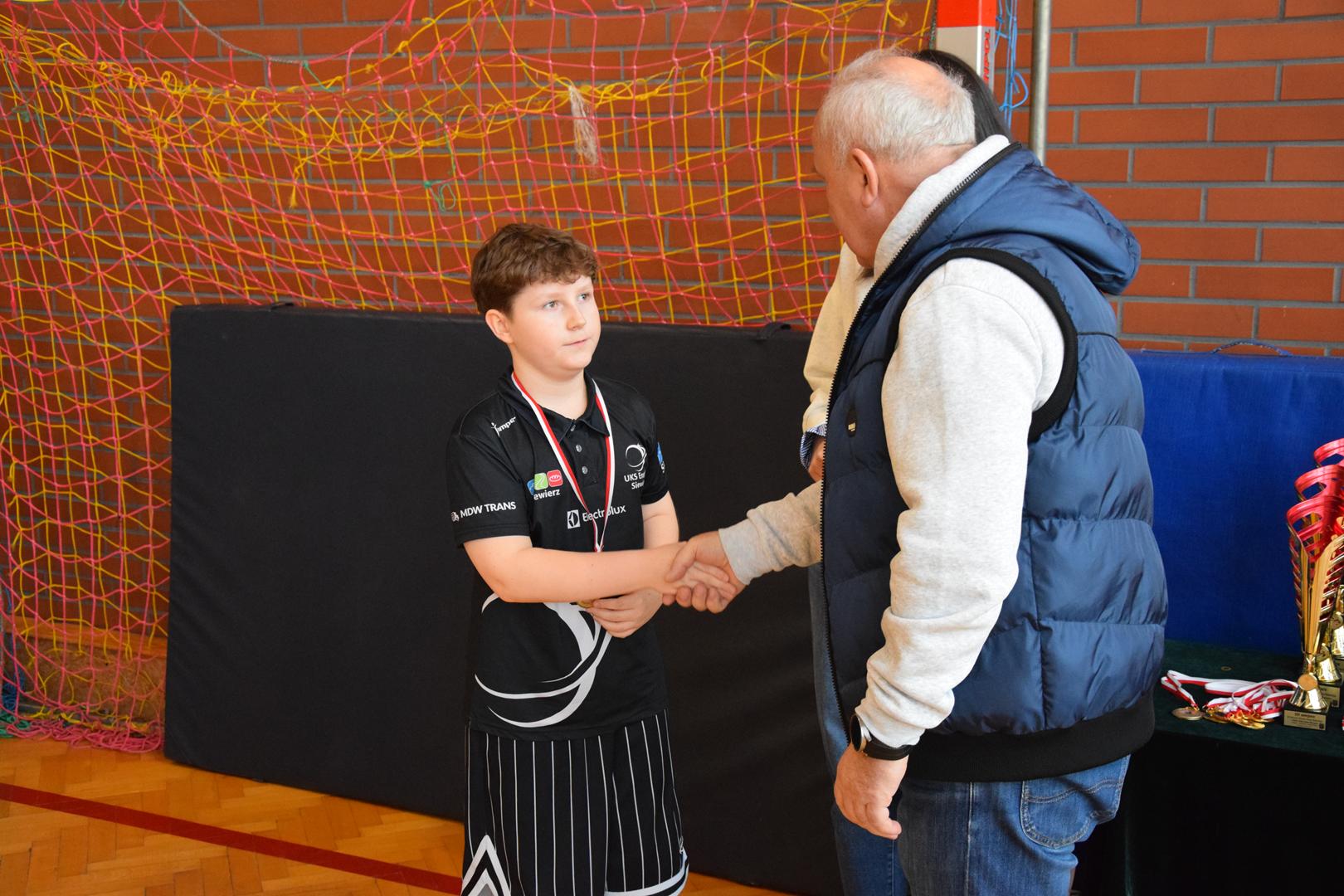 Zdjęcie przedstawia moment wręczania medali, dyplomów i pucharów