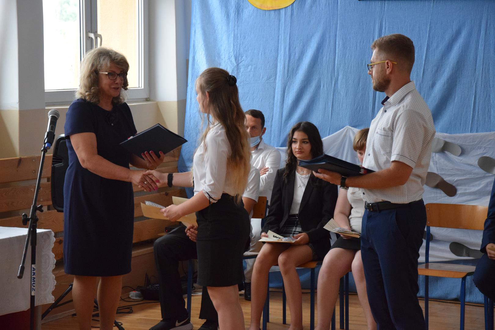 Zdjęcie przedstawiające moment rozdania świadectw przez dyrektor szkoły podstawowej w Przeczycach Małgorzaty Drzewieckiej