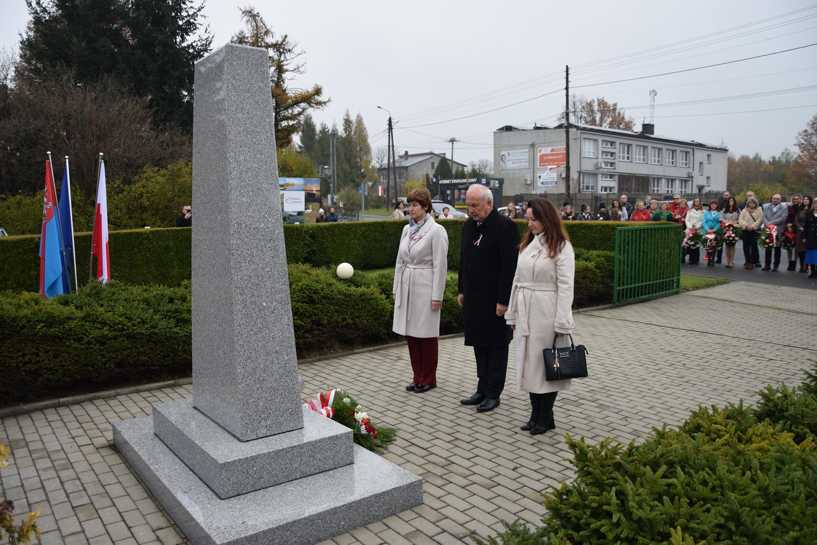 Zdjęcie przedstawia moment składania kwiatów pod pomnikiem