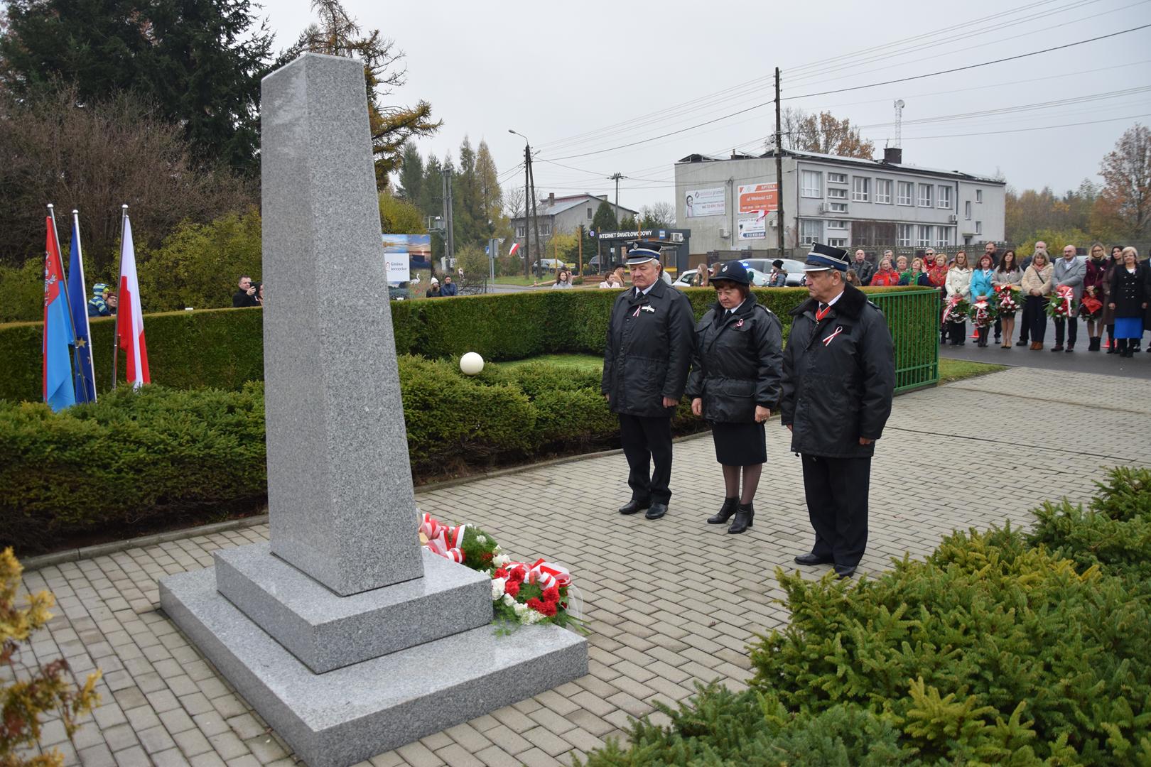 Zdjęcie przedstawia moment składania kwiatów pod pomnikiem