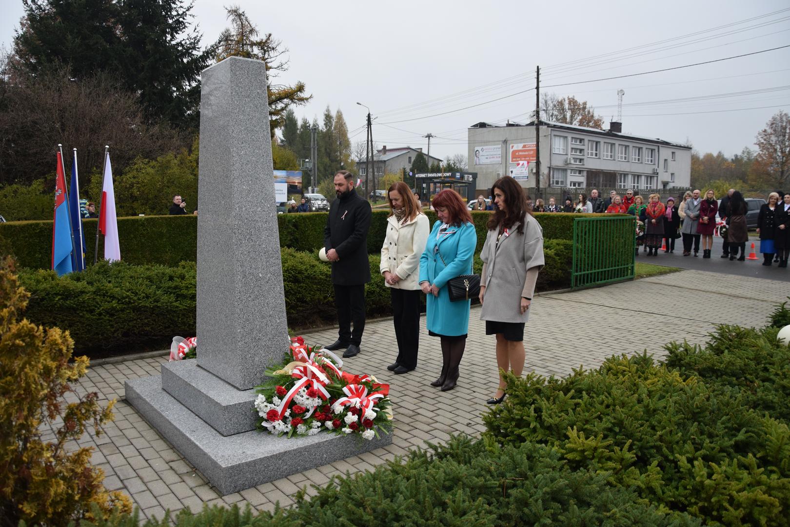 Zdjęcie przedstawia moment składania kwiatów pod pomnikiem