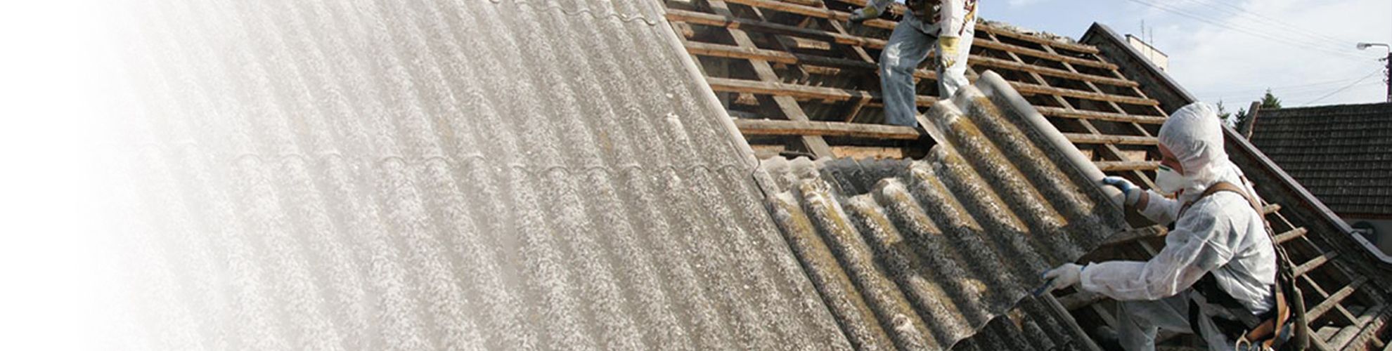 Widok na pracowników demontujących azbest na dachu